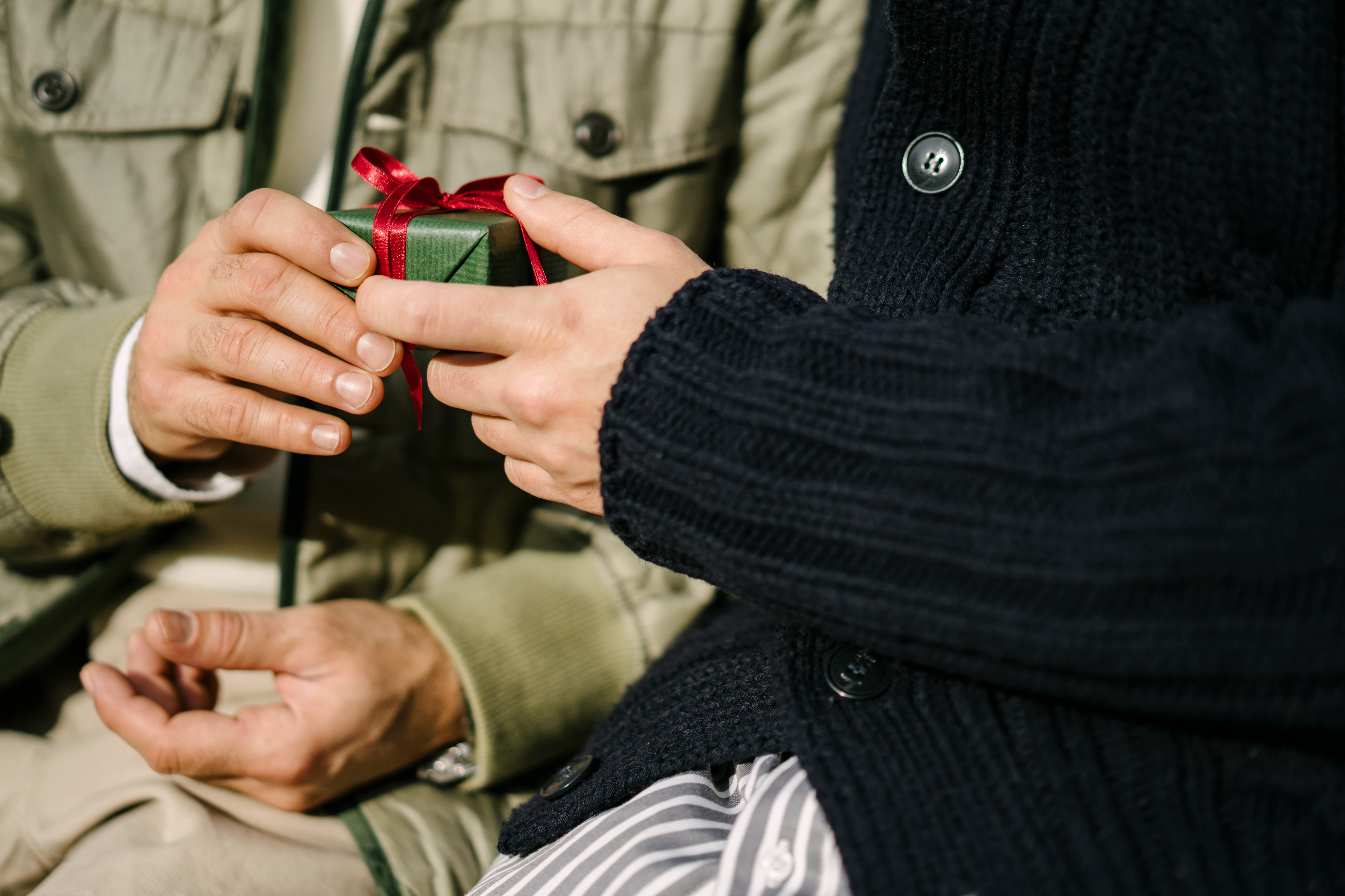 Hands exchanging a small gift wrapped with a ribbon