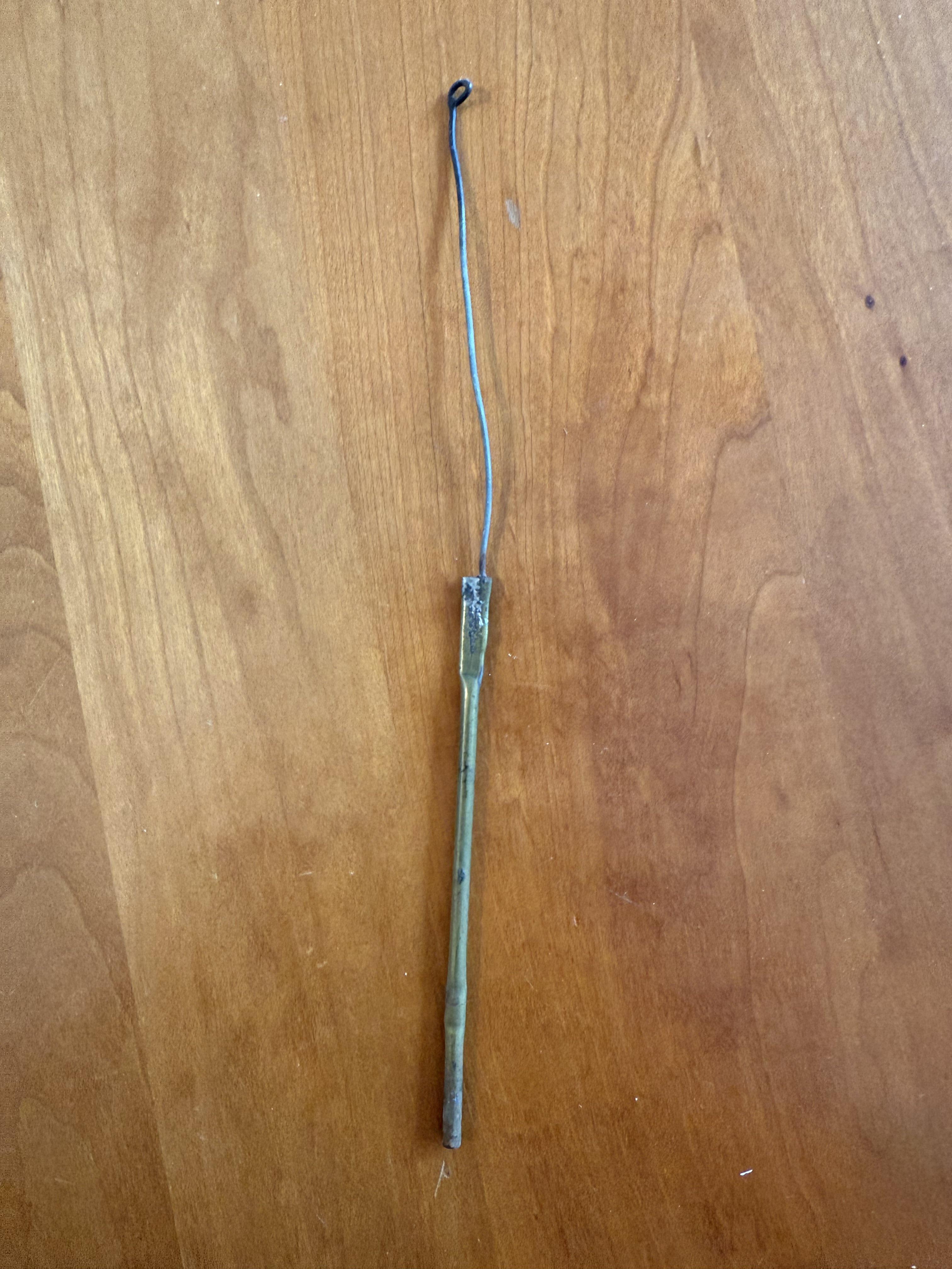 A metal rod with a loop at the end, resting on a wooden surface