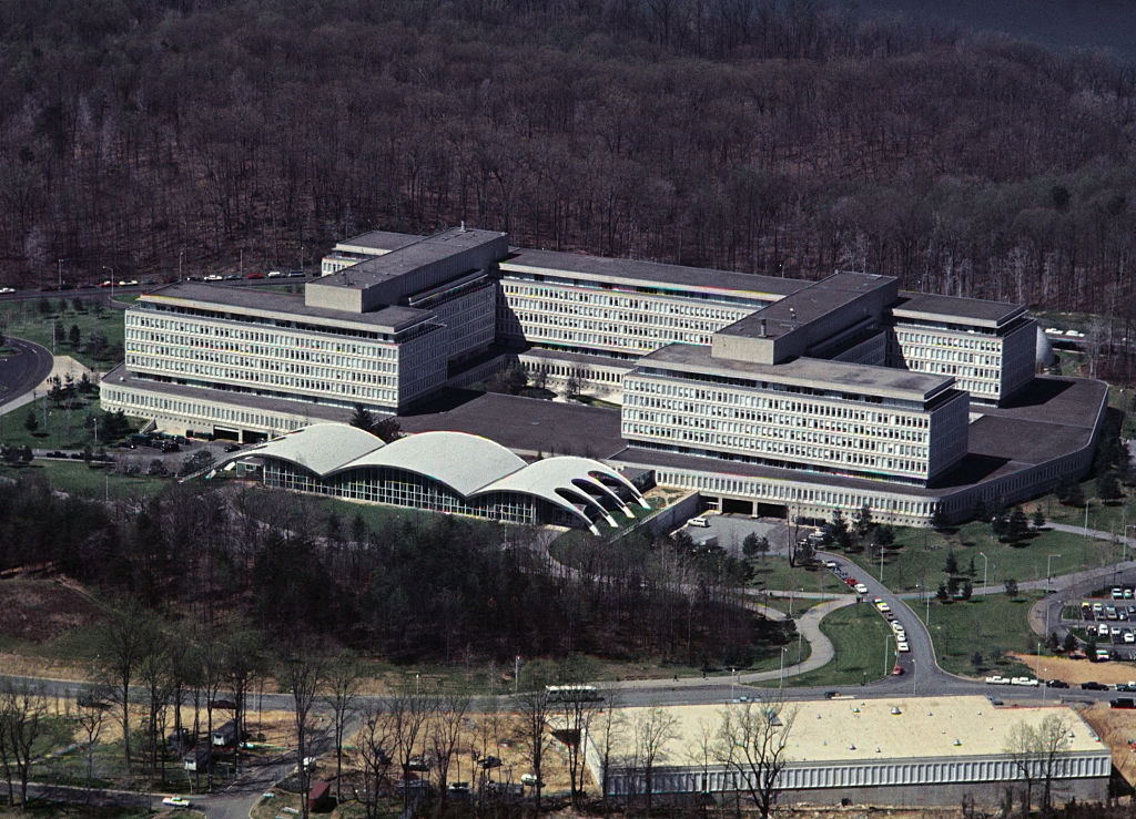 Aerial view of a large government office complex surrounded by trees and a road