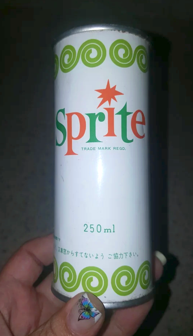 A hand holding a 250ml can of Sprite with retro design