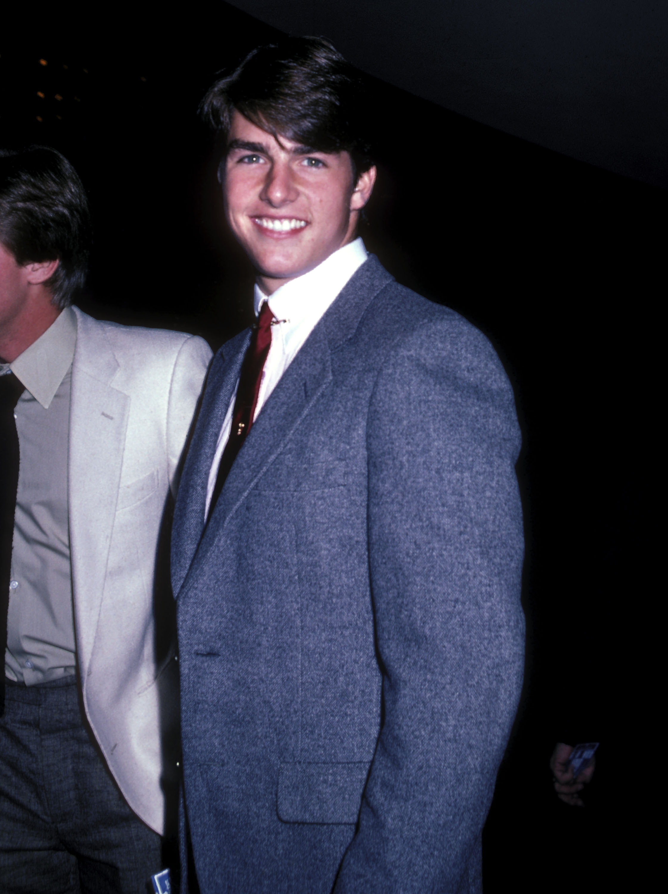 Person in a suit with a crisp shirt and tie, smiling at an event