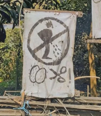 Sign showing a person urinating in a circle with a slash through it, indicating no urination, with additional graffiti below the sign