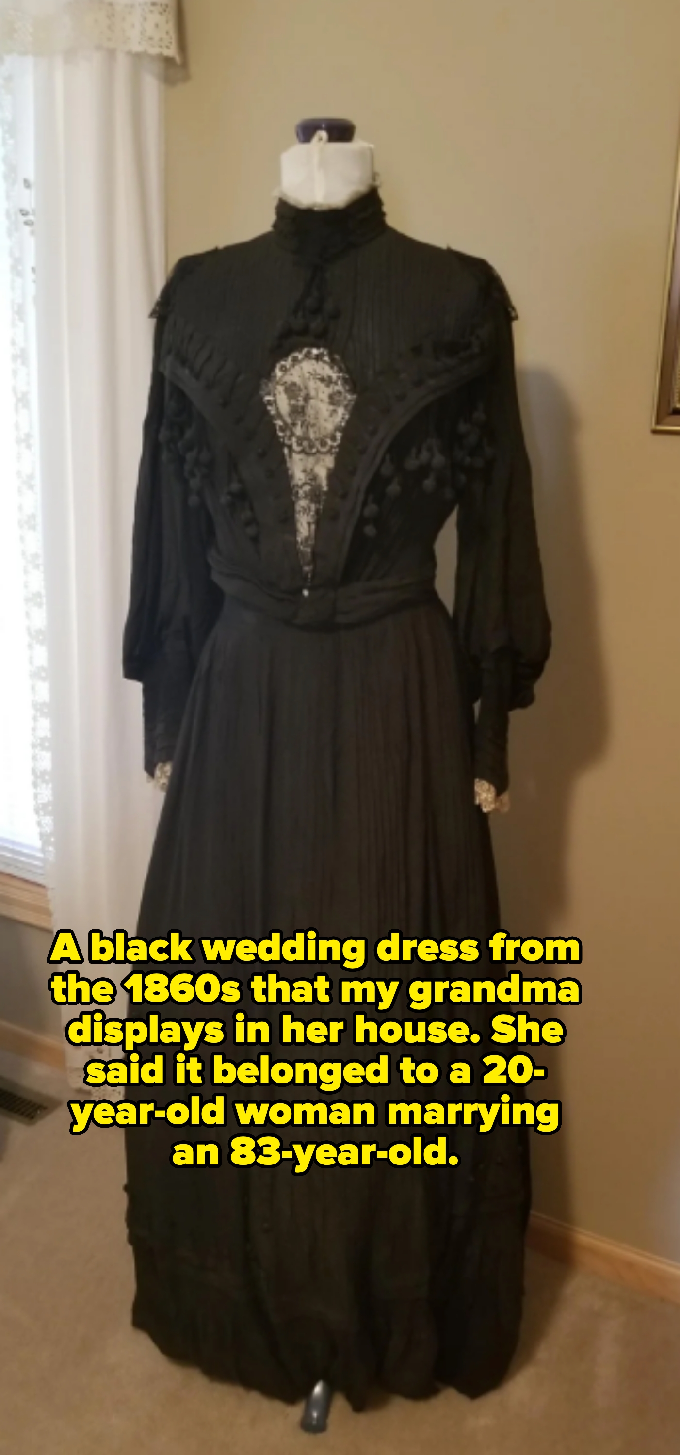 Antique black Victorian-style dress on a mannequin, featuring lace detailing and long sleeves. Caption: "A black wedding dress from the 1860s that my grandma displays in her house. She said it belonged to a 20-year-old woman marrying an 83-year-old"