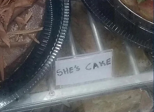 A bakery display sign humorously labeled "She's Cake" is visible among dessert items