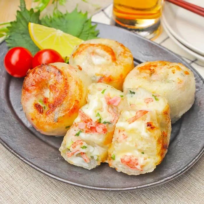 お皿に盛られた4個の海鮮風タコ焼き。1個は半分に切られ、中の具が見える。背景に飲み物と箸がある。