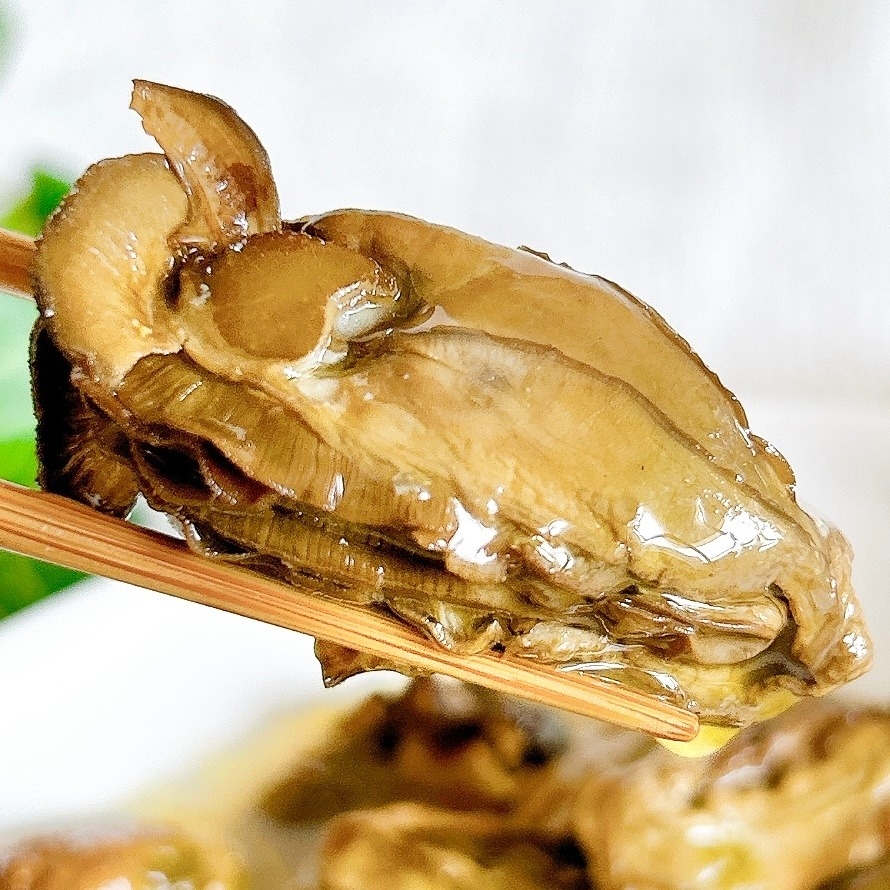 箸で持たれたカキ。料理の詳細は不明。