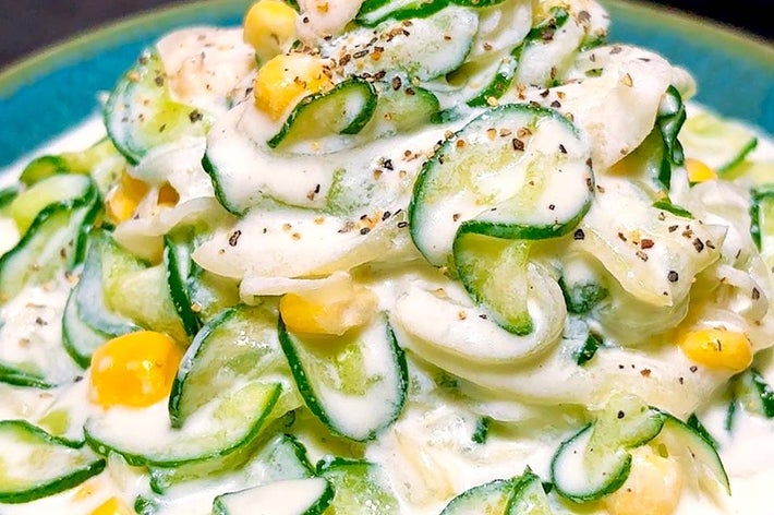 クリーミーなソースで和えた、キュウリとコーンのサラダが青い皿に盛られている。