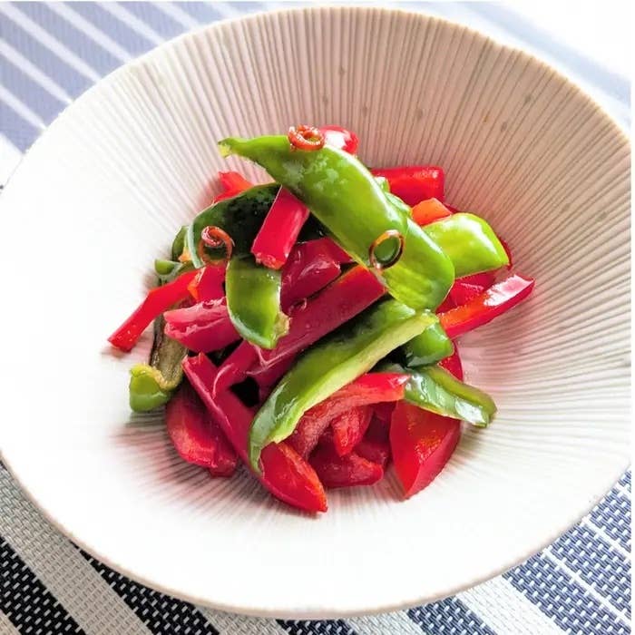 皿に盛られた赤と緑のパプリカの炒め物。シンプルで美しいプレゼンテーション。