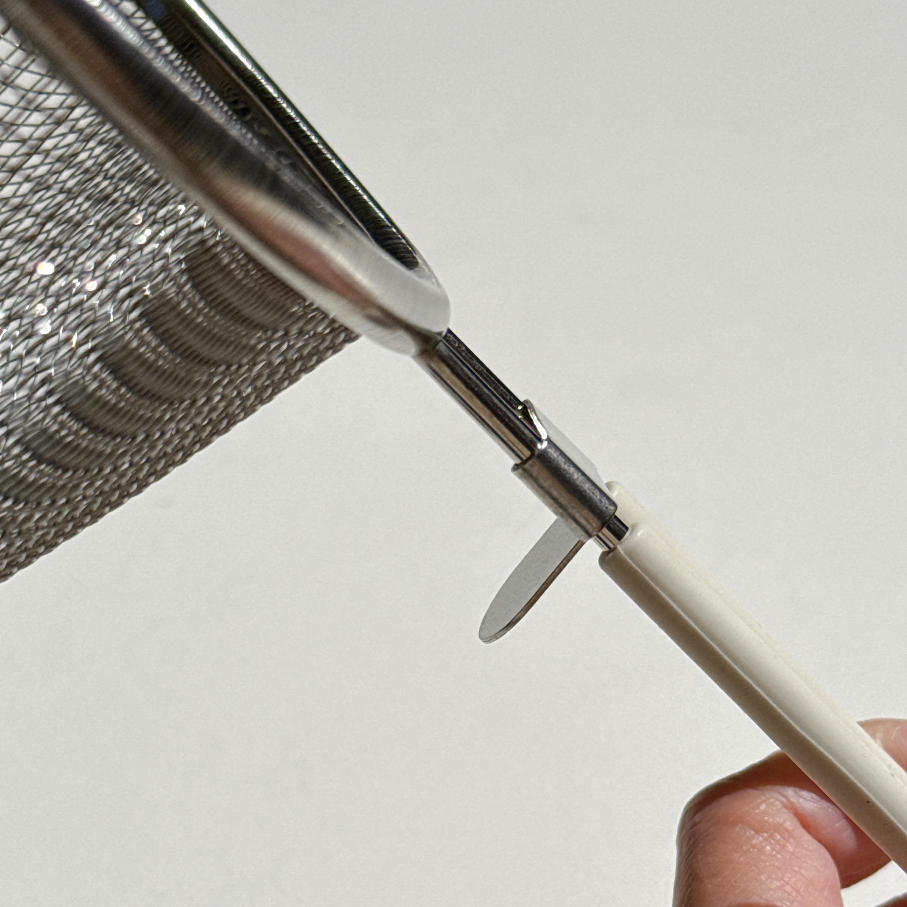 金属メッシュの調理器具がシルバーのハンドルに取り付けられている様子が写されています。