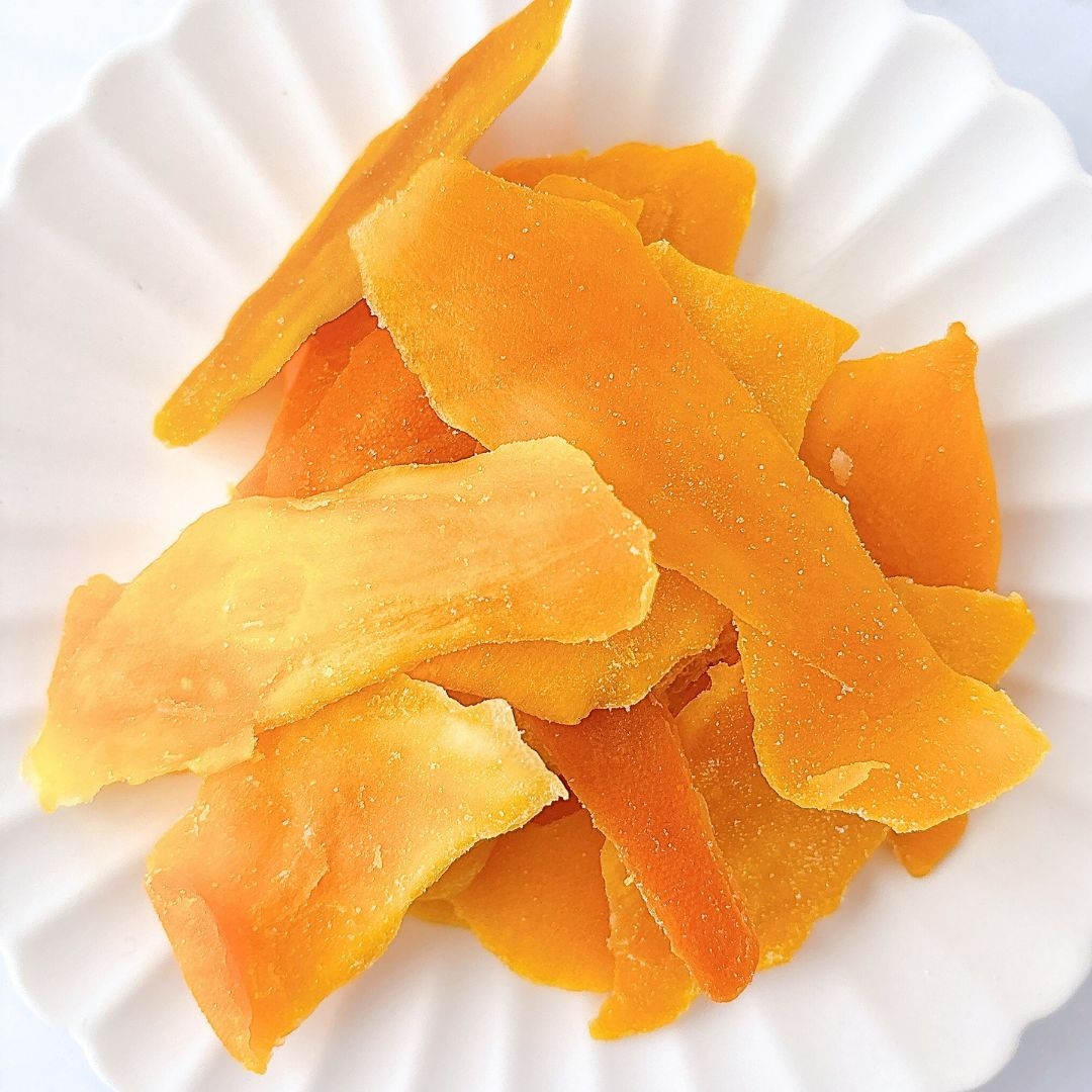 白い皿に盛られた乾燥マンゴーの薄切り。