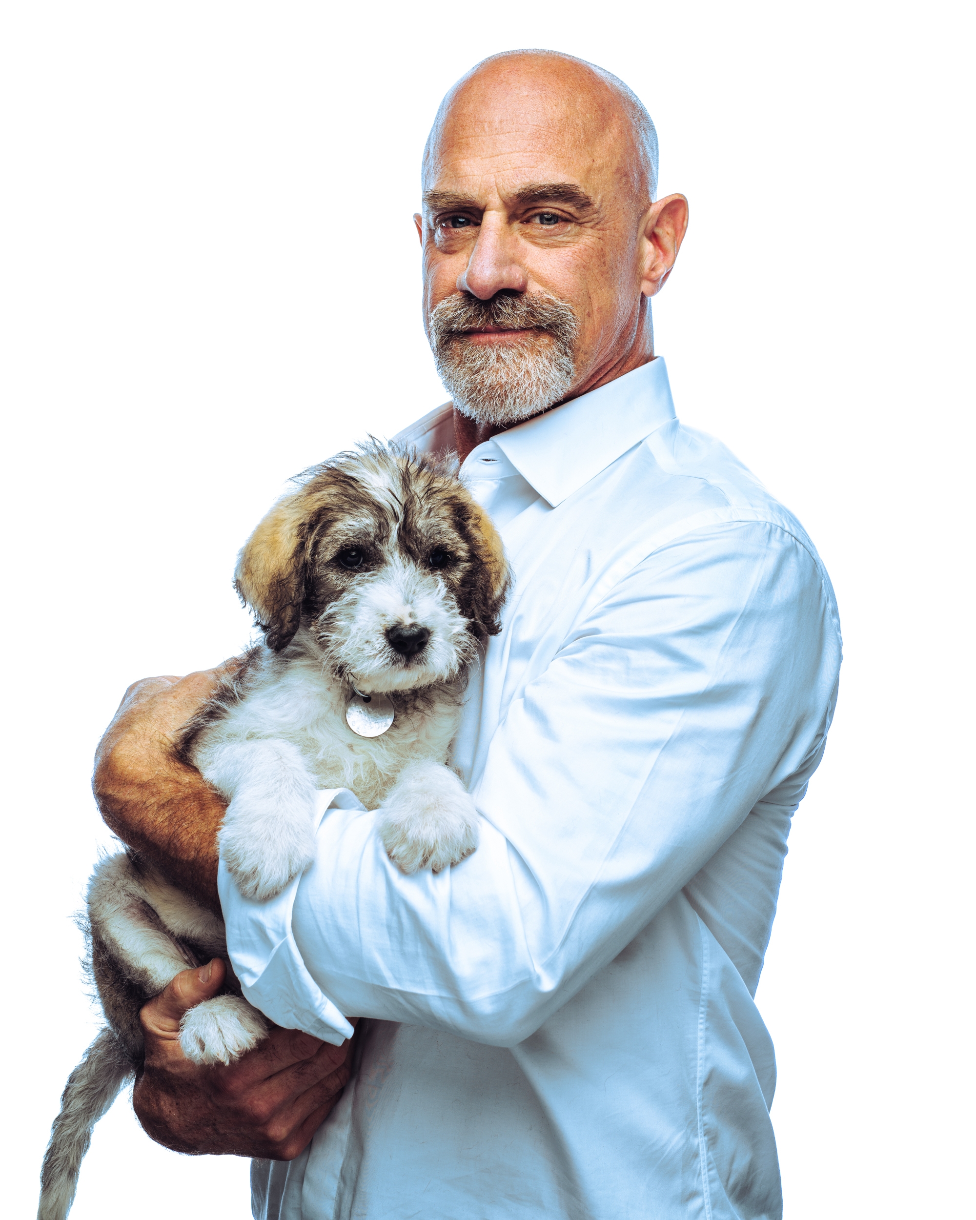 Chris holds a fluffy dog in his arms, wearing a crisp white shirt