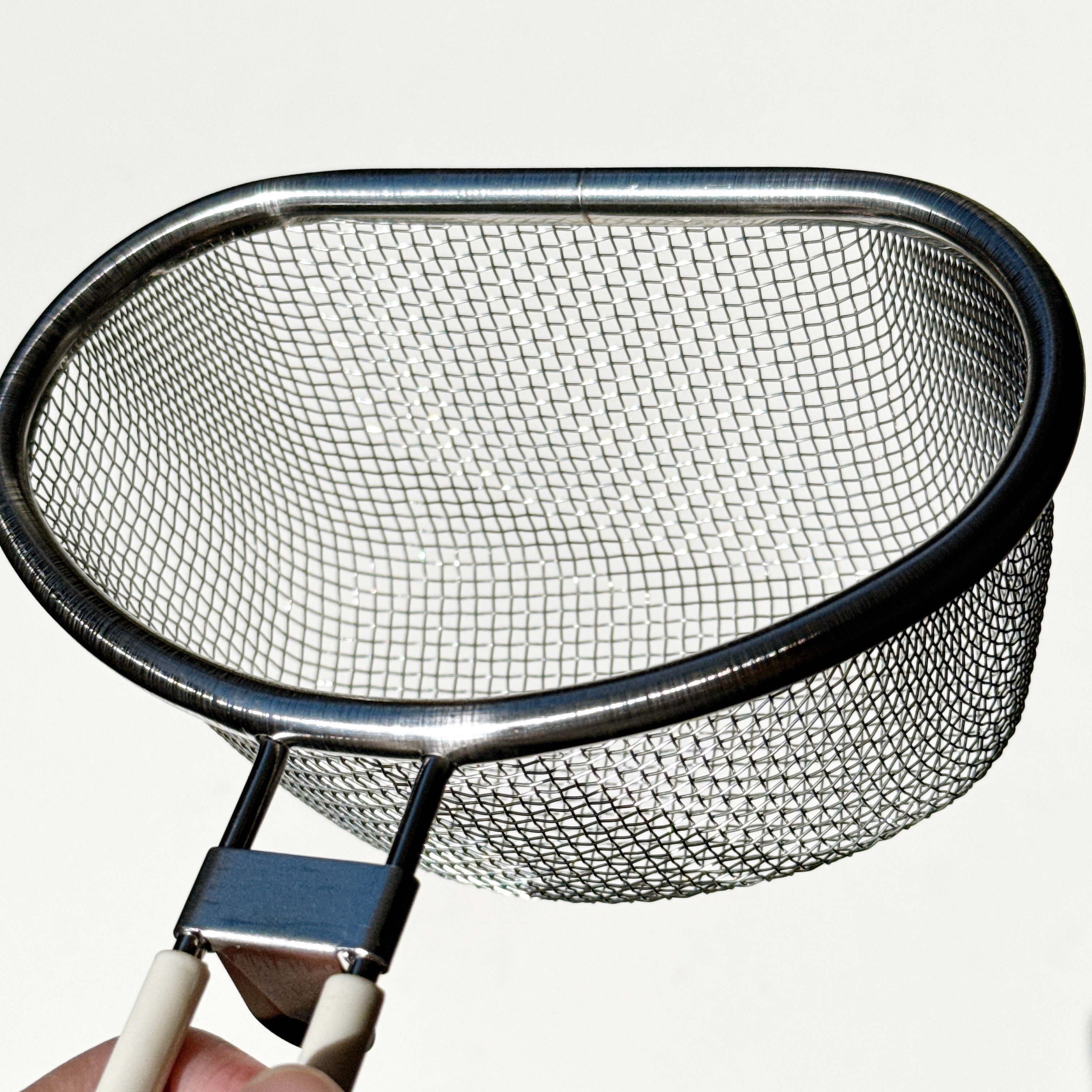 手に持たれた金属製のワイヤー製ざる。用途は不明。