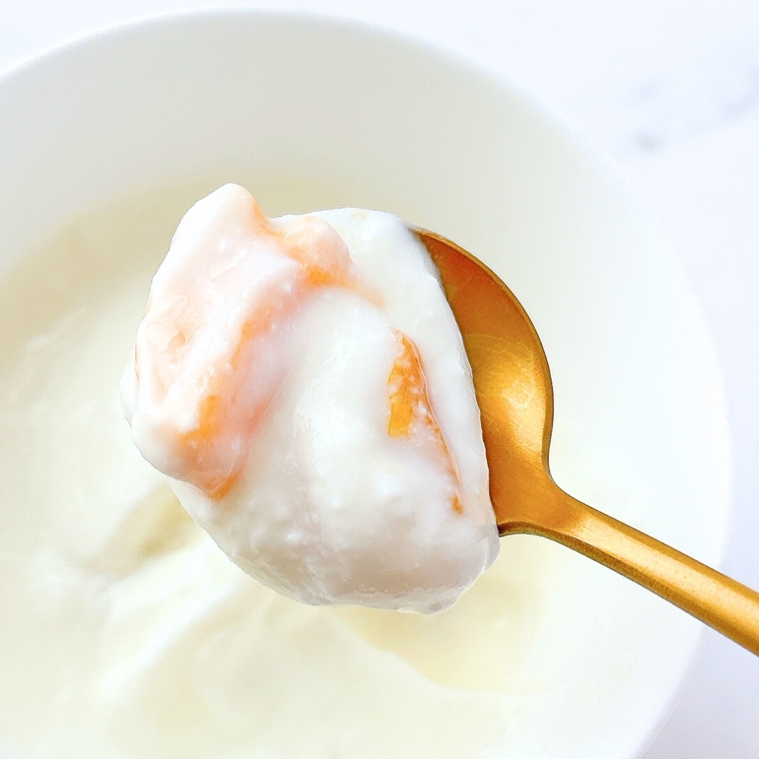 スプーンでヨーグルトをすくい上げた様子。果物入り。