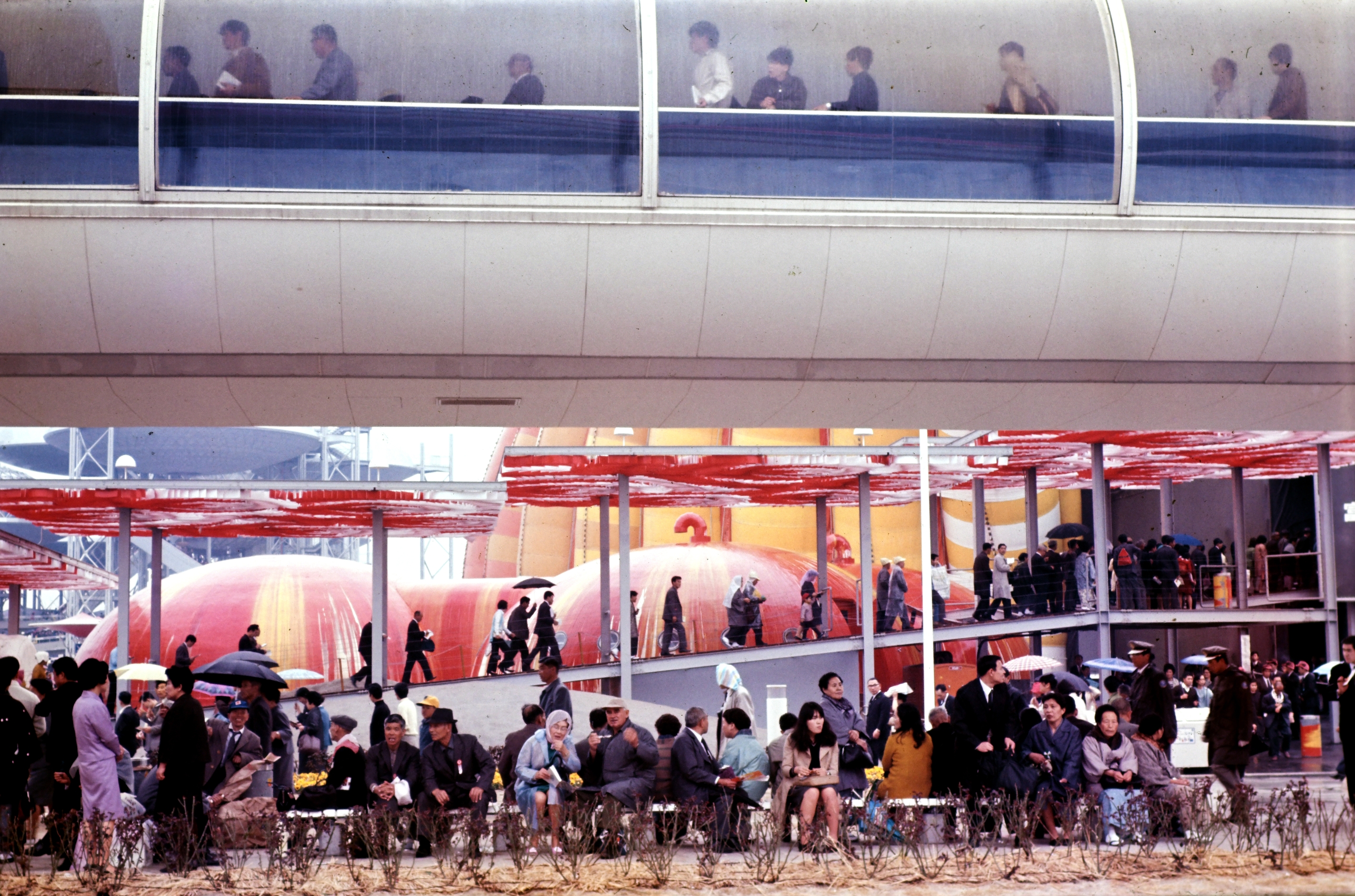「動く歩道」(上)の下で雨宿りする入場者たち(1970年撮影/時事)