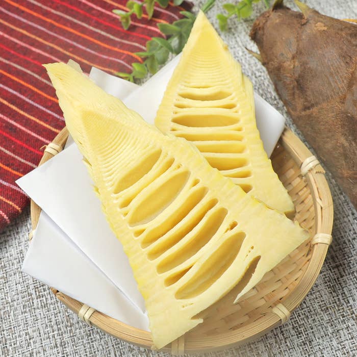 竹の子のスライスがカゴに盛られています。背景に葉や布が見えます。