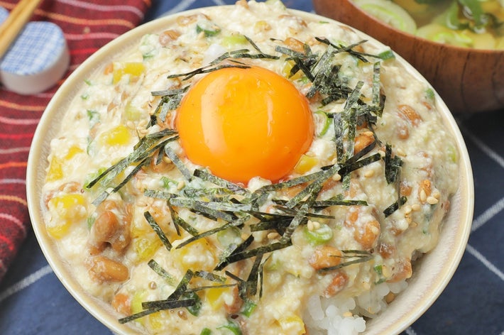 米に納豆、刻み海苔、卵黄がトッピングされた丼と、わかめスープが並んでいます。