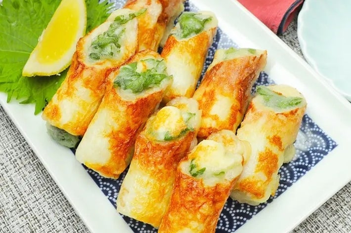 皿に盛られた焼きチクワの中に青菜が詰まっている料理。添えられたレモンが新鮮さを引き立てる。