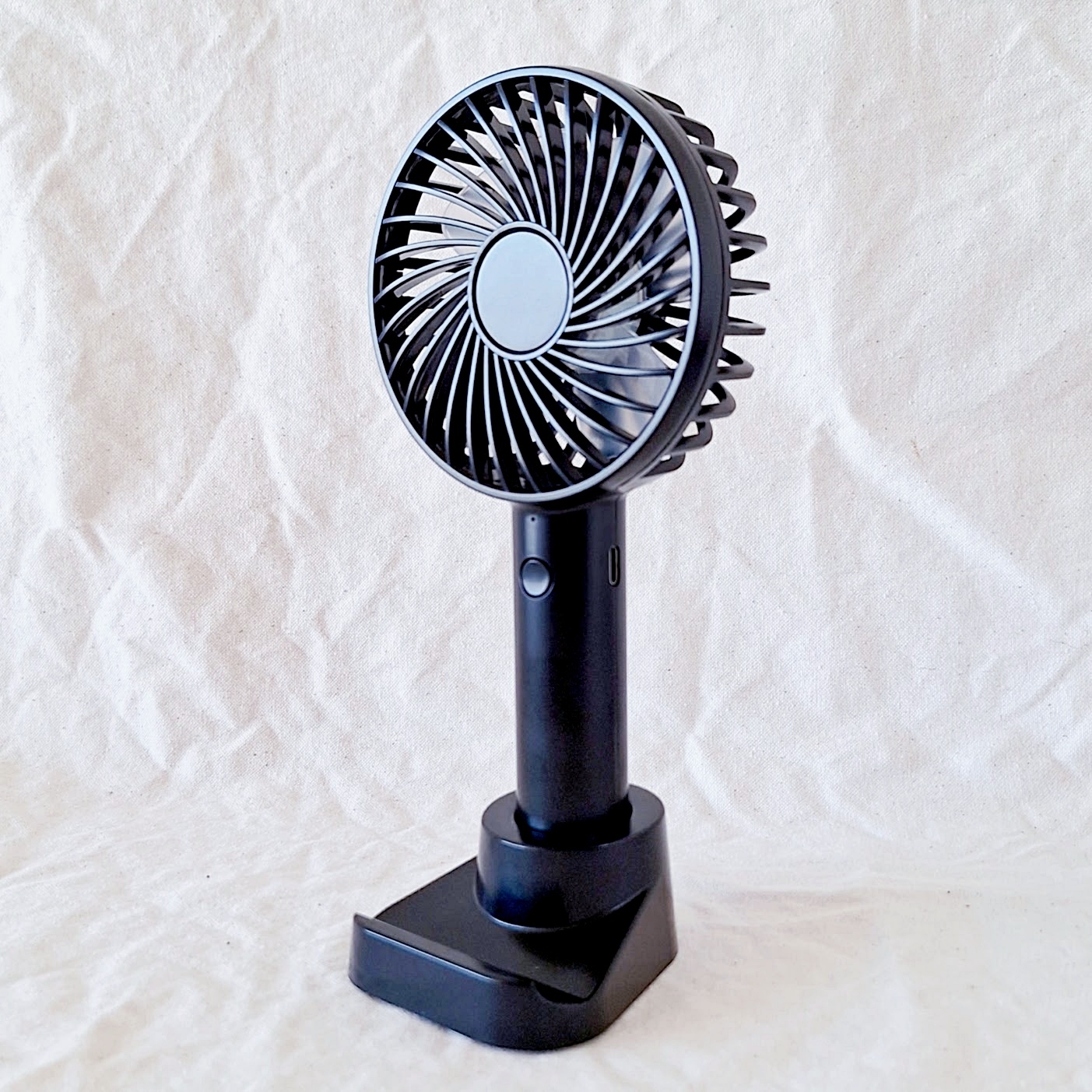 卓上型の電動ファンが白い背景に置かれている。シンプルでモダンなデザイン。