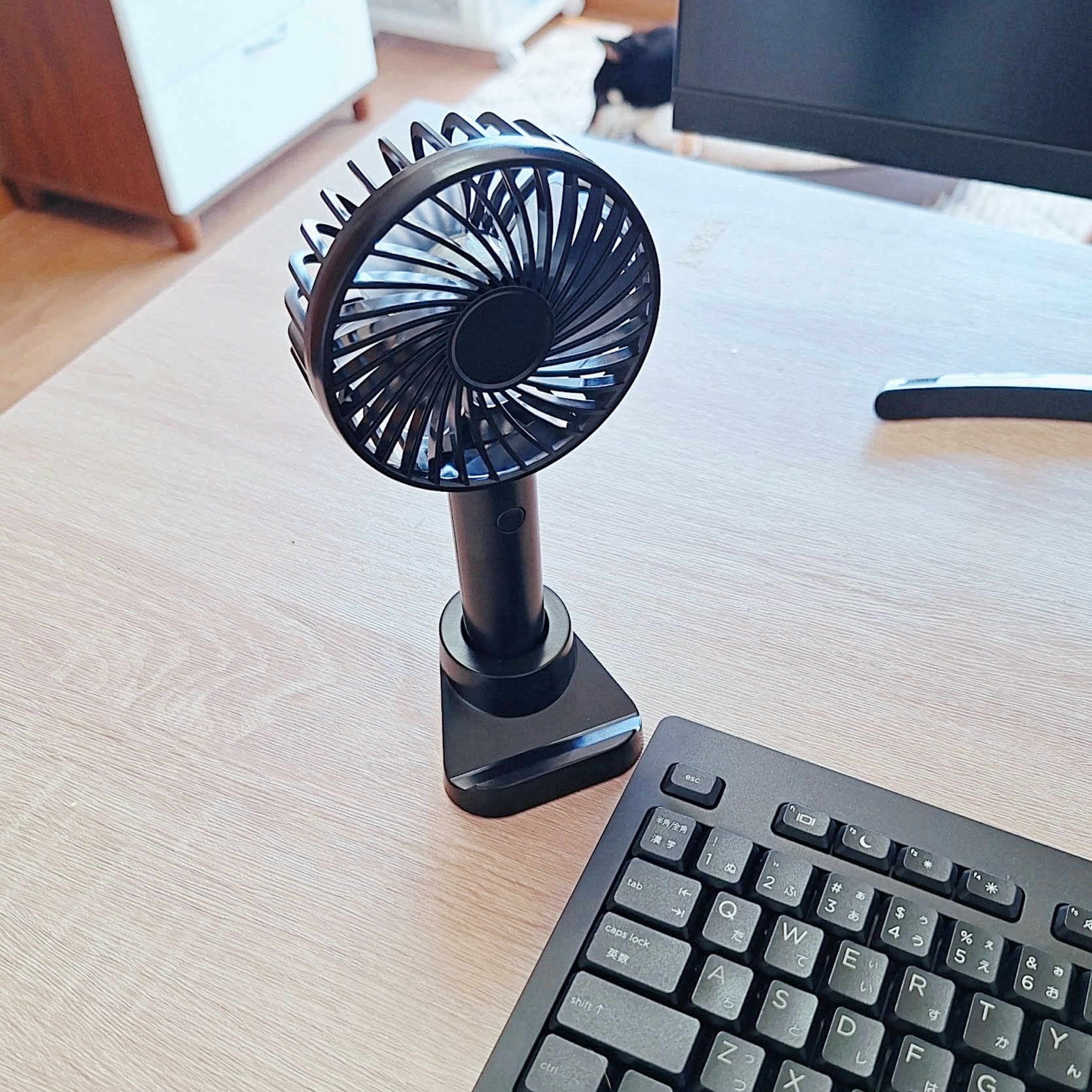 机の上に置かれた小型の卓上扇風機とキーボード。