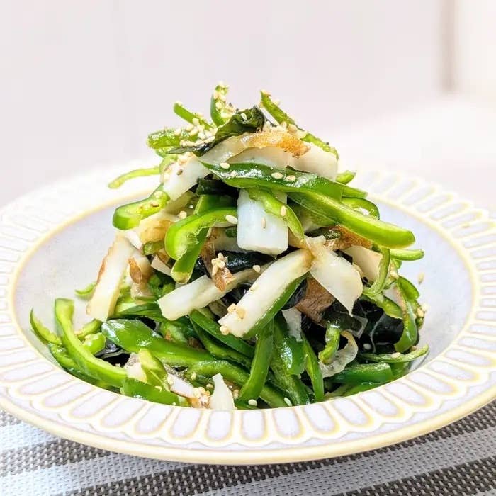 野菜の和え物が白い皿に盛られている。細切りのピーマンやキャベツが含まれている。