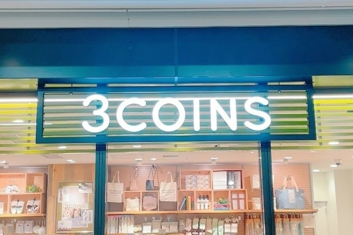 店舗「3COINS」の看板と商品が並ぶショーウィンドウ。シンプルで実用的な生活雑貨が並ぶ。