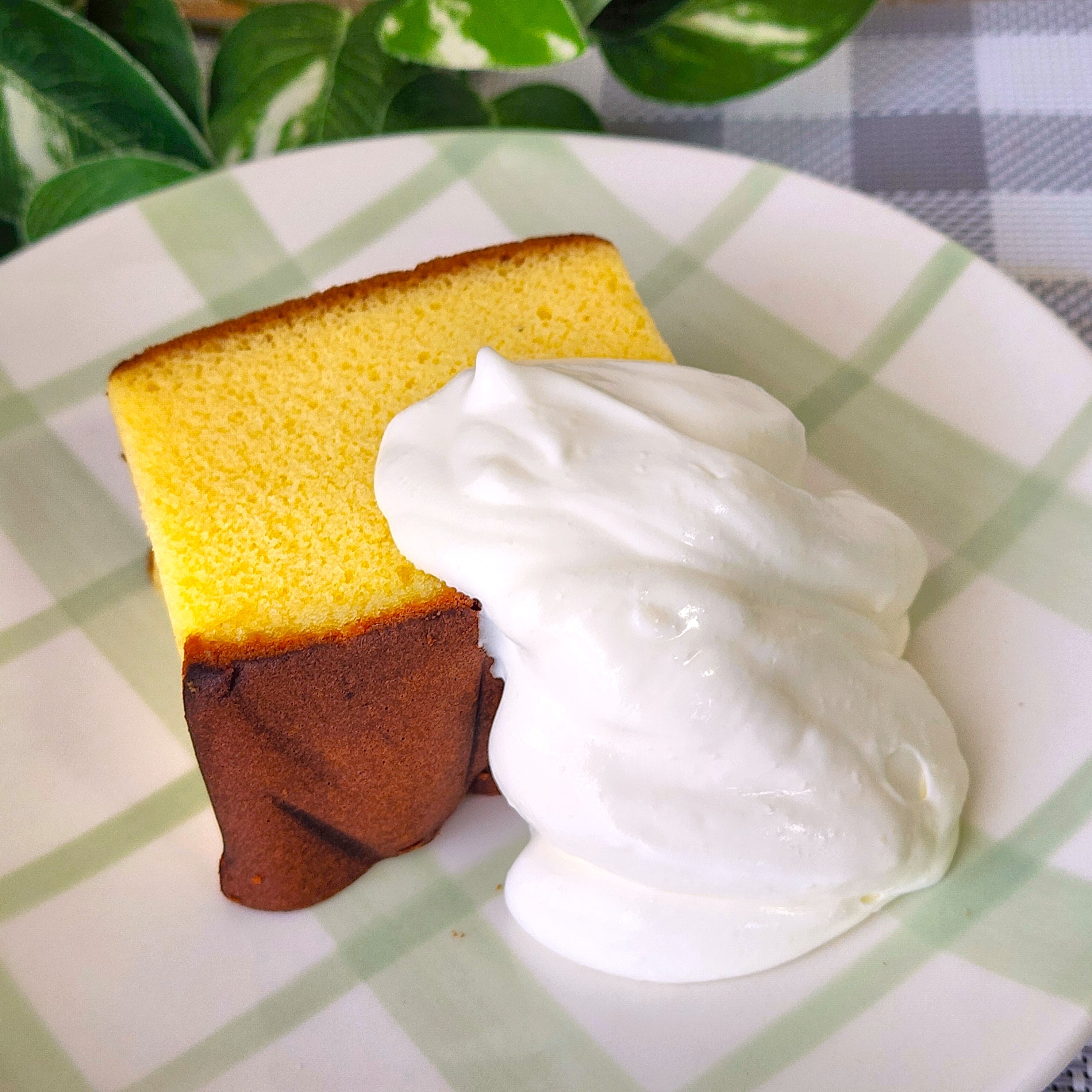 ケーキとクリームが皿に盛られている。背景には観葉植物が見える。