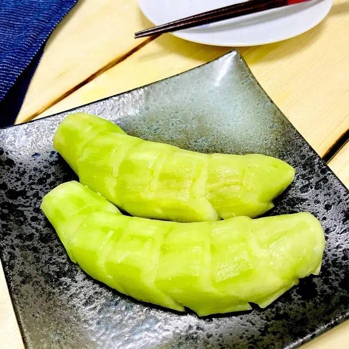 黒い皿にカットされたメロンが2切れ、テーブルに置かれています。