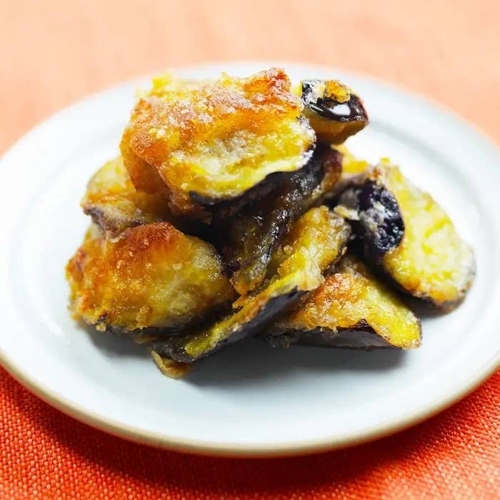 白い皿に盛られた焼きスイートポテト。砂糖がまぶされた甘いスイーツが山盛りになっている。