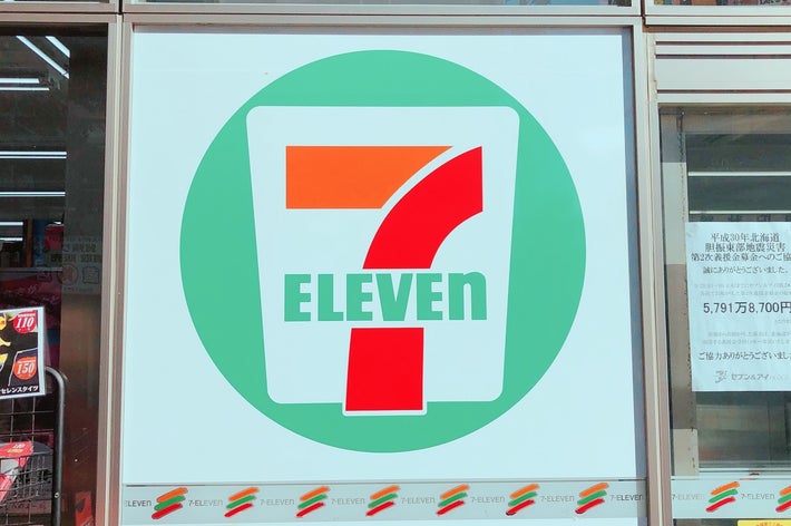 セブンイレブンの店舗のガラス窓に大きなロゴが表示されている。