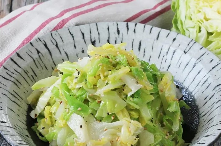 皿に盛られた炒めたキャベツ料理。背景にキャベツの一部が見える。
