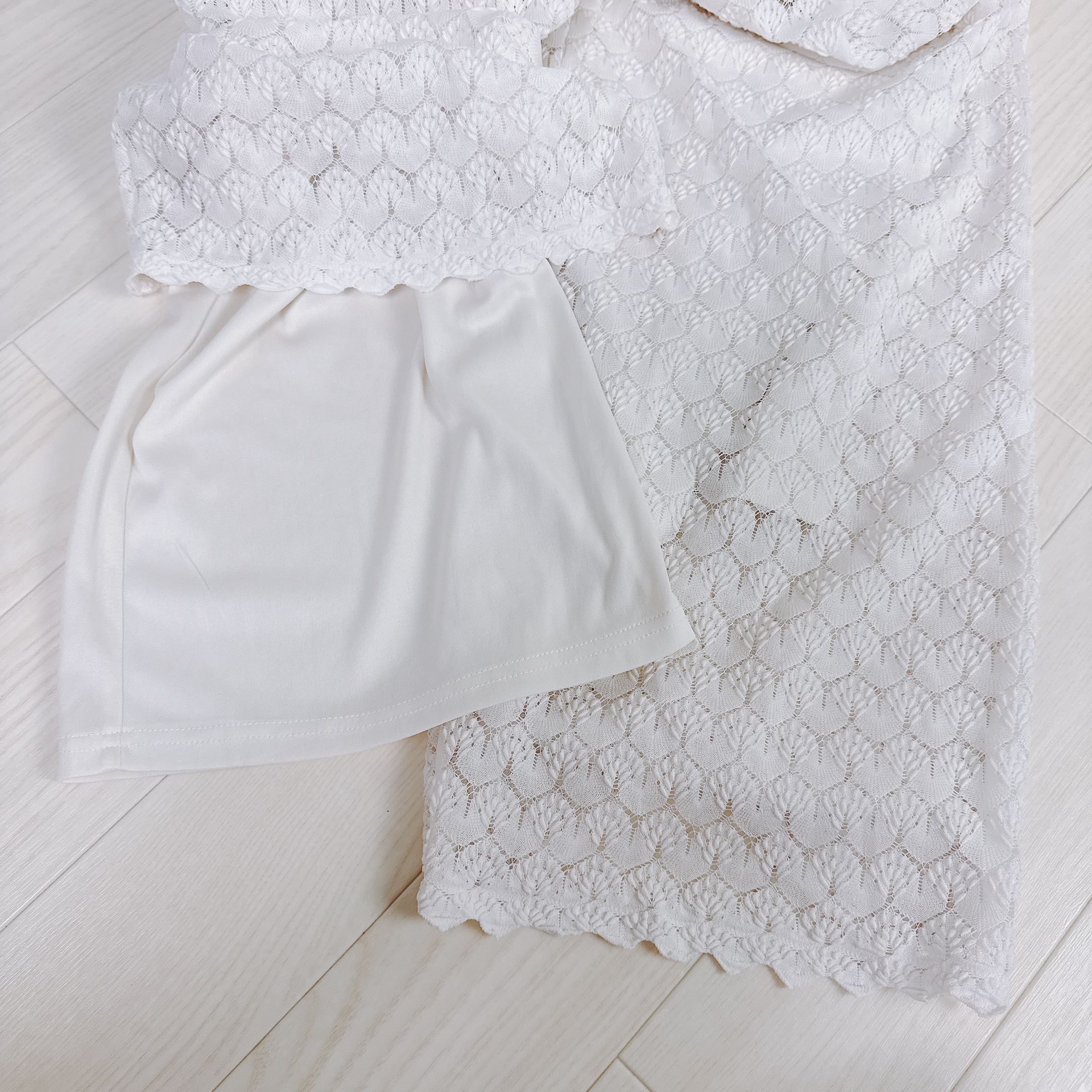 Textured white fabric with an overlapping plain white section laying on a light wooden floor