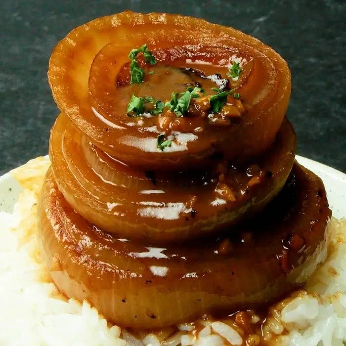 玉ねぎの輪切りが積み重なり、ソースとパセリが掛かっている料理。下にはご飯が敷かれている。