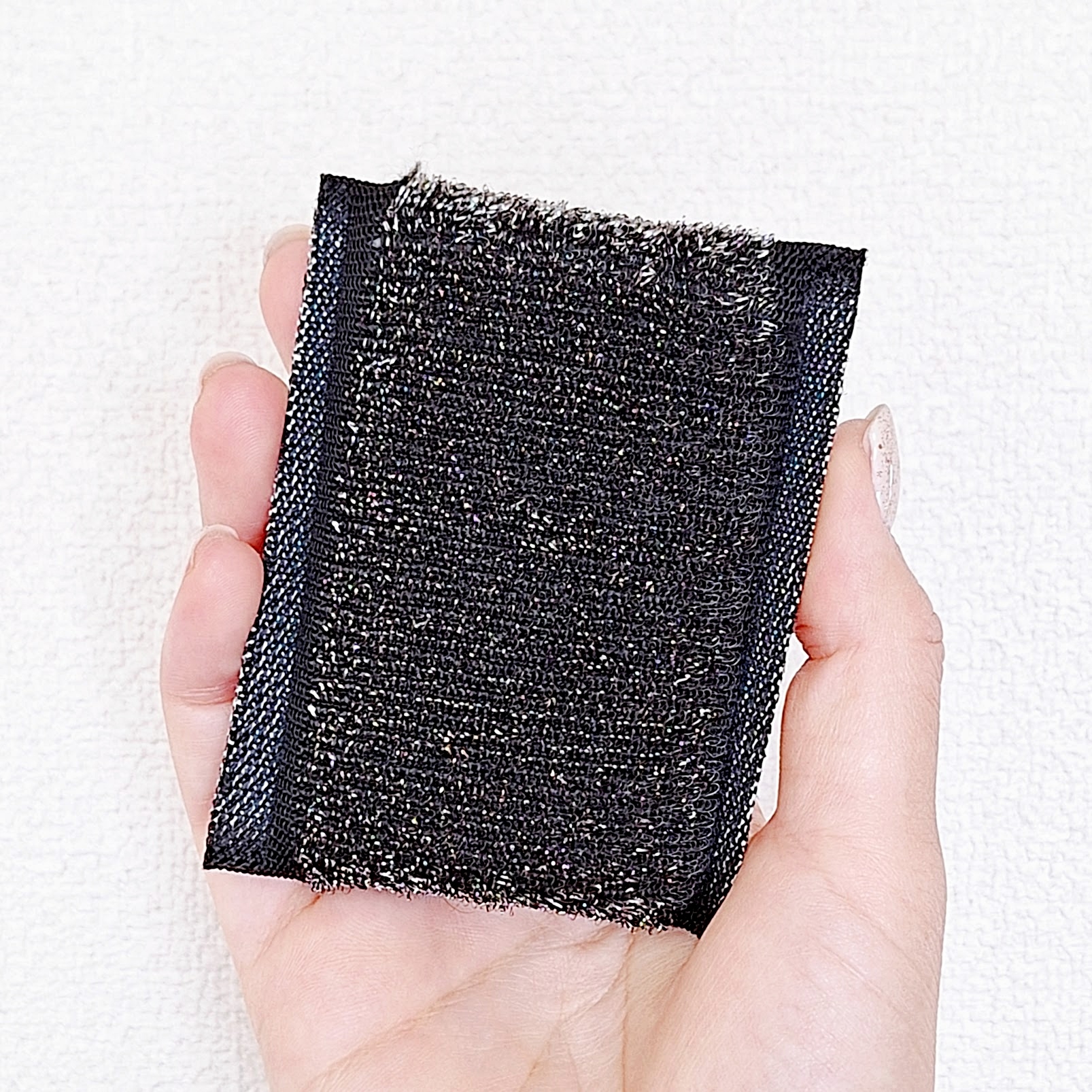 手のひらに載せたブラックのスクラブパッド。