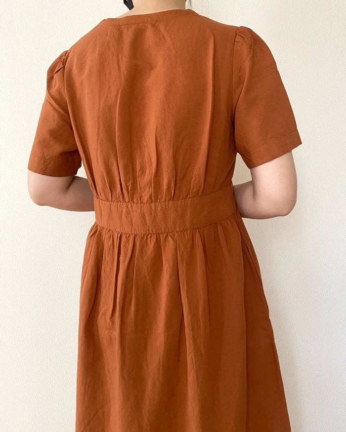 Person in a simple, short-sleeve dress with a fitted waist, viewed from the back