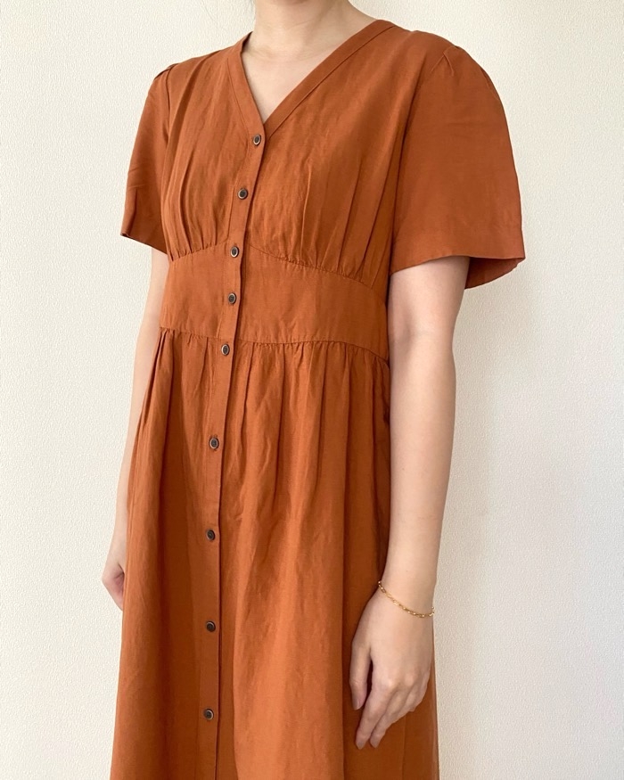 Person in a short-sleeved, buttoned dress with a fitted waist and flowing skirt, standing sideways