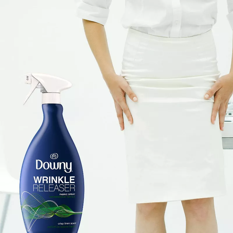 Person in white outfit using Downy Wrinkle Releaser spray bottle