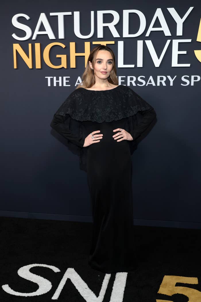 Person in an elegant, long black dress poses at a "Saturday Night Live" anniversary event