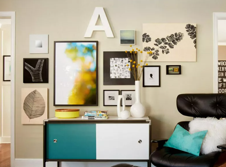 Eclectic gallery wall in a stylish living room, featuring varied framed artworks and prints, with a modern sideboard and cozy armchair