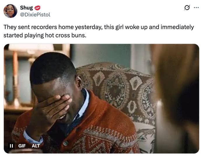 A person covers their face with one hand while sitting, appearing amused or overwhelmed