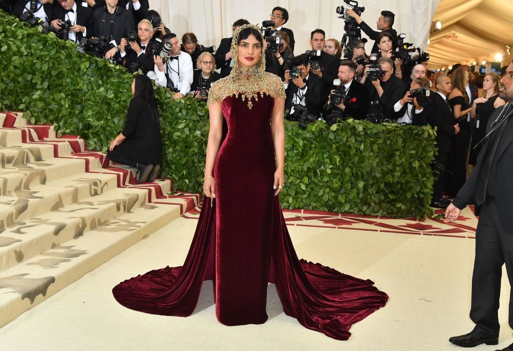 Priyanka in an elegant, high-neck, velvet gown with ornate embellishments and a hood