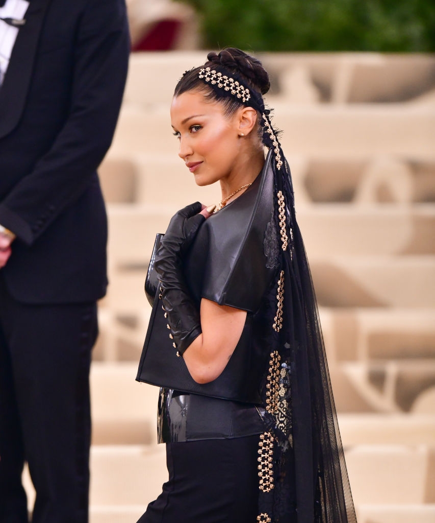 Bella in a stiff leather outfit with gold accessories and long veil