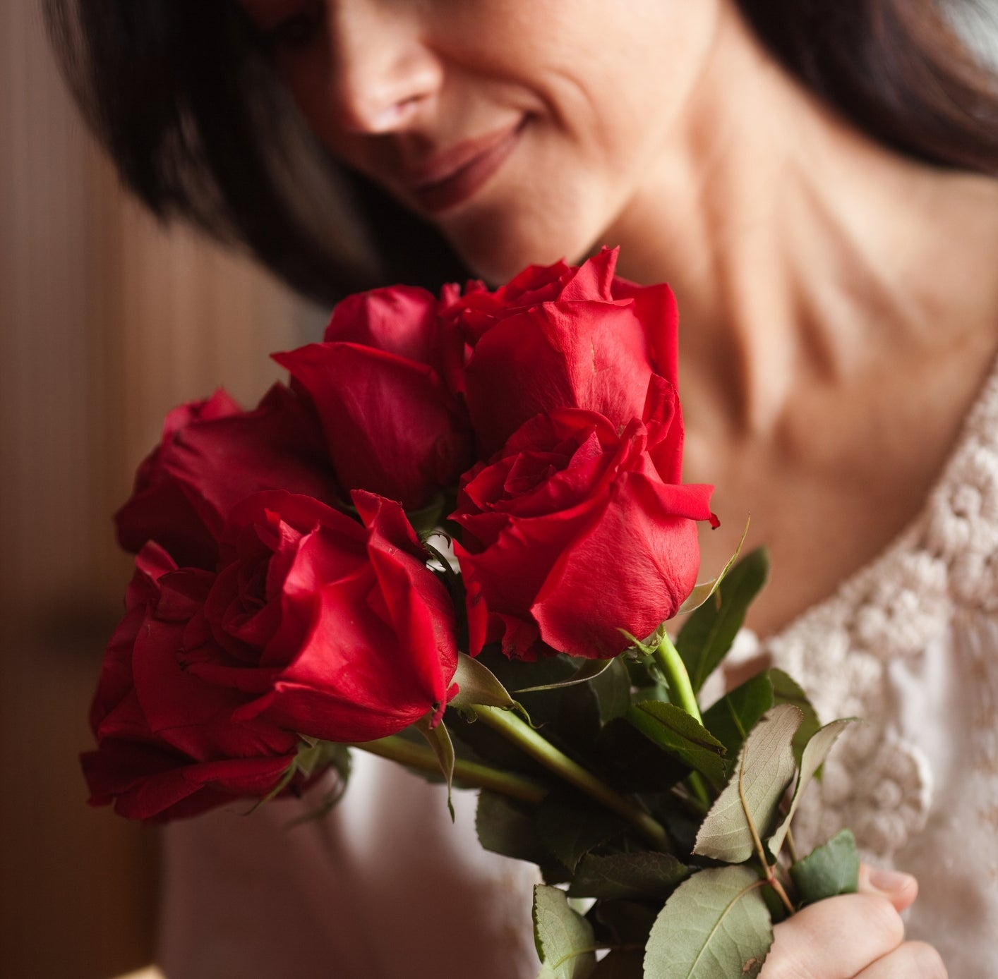 Person holding a bouquet of roses, smiling gently