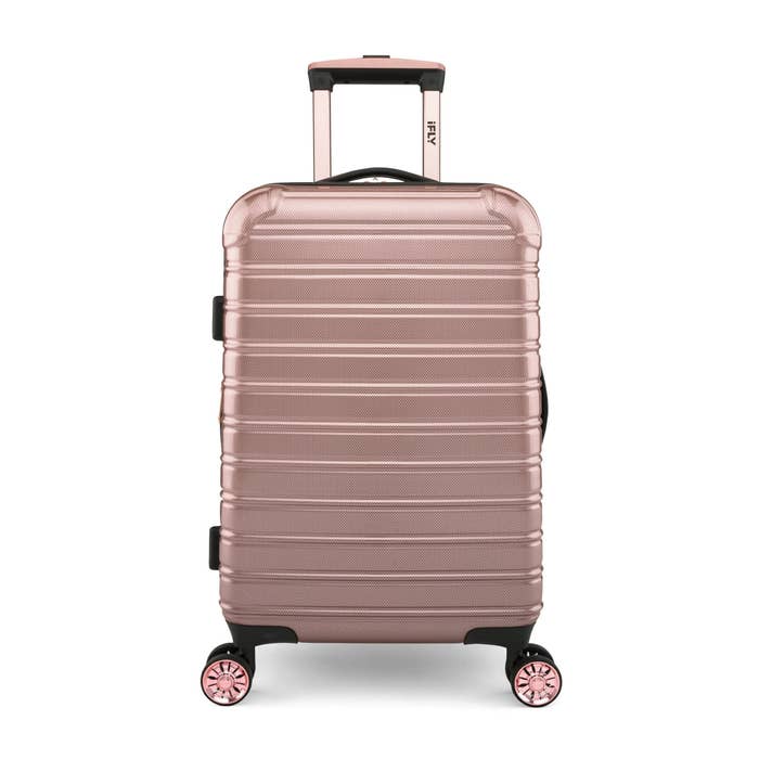 A hardshell suitcase with a textured finish, telescopic handle, and spinner wheels, suitable for travel