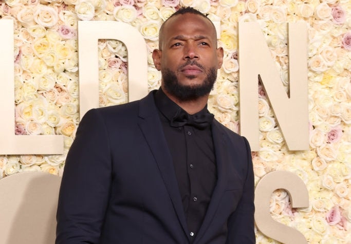 Person in a dark suit and bow tie on a floral backdrop at a formal event