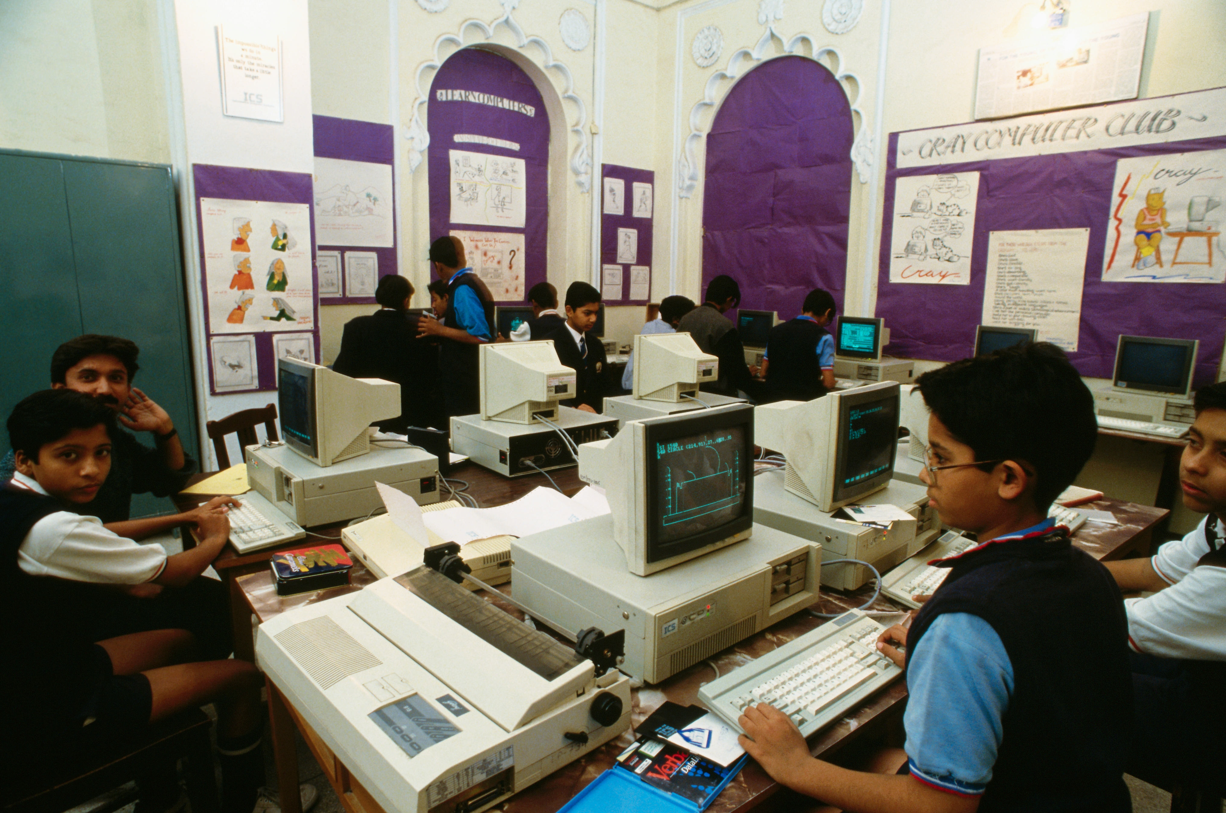 Classroom with students using vintage computers, engaged in learning or activities, surrounded by educational posters