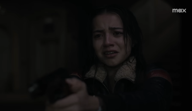 Mujer en una escena dramática sujeta un arma con expresión de angustia. Viste chaqueta de cuero