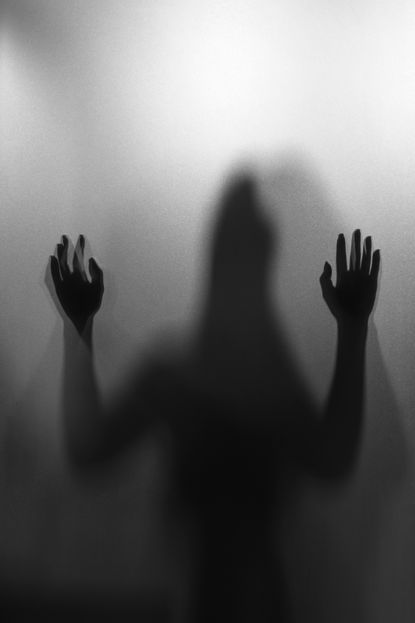 Silhouette of a person with raised hands behind frosted glass, creating a mysterious atmosphere