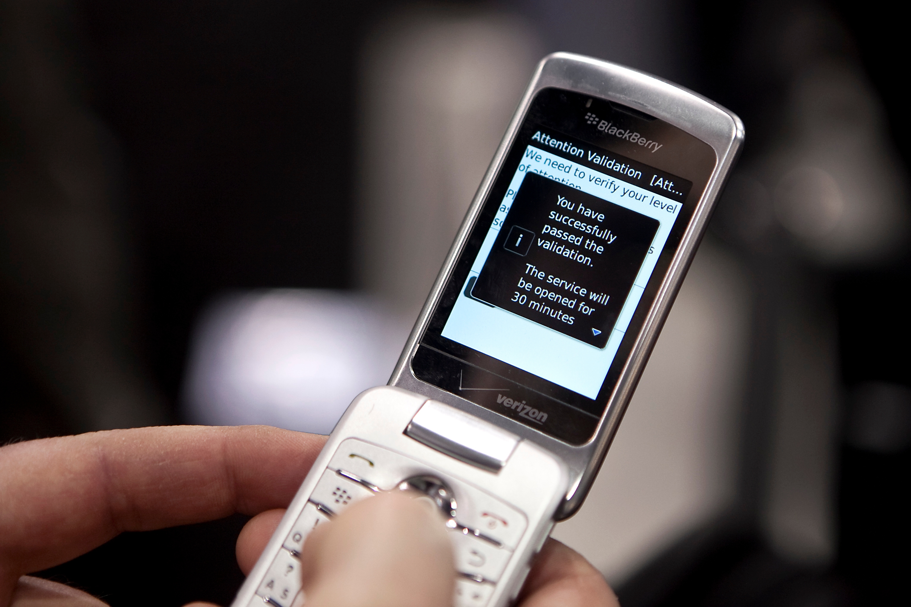 Hand holding an open flip phone displaying a message about successful validation and a 30-minute service access
