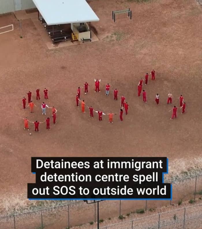 Aerial view of detainees at an immigrant detention center forming "SOS" on the ground, calling for help