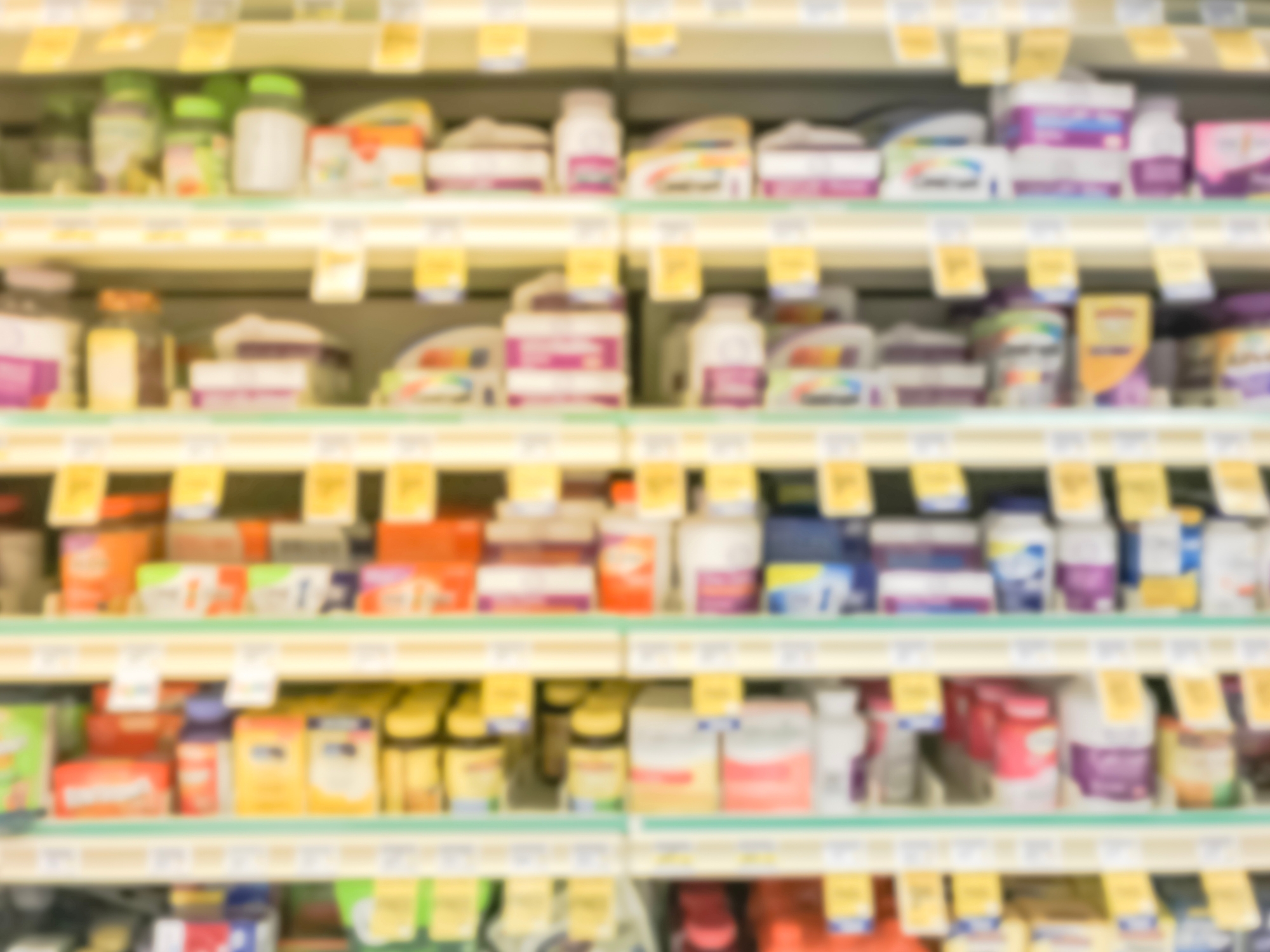 Blurred view of neatly arranged vitamins and supplements on store shelves with price tags